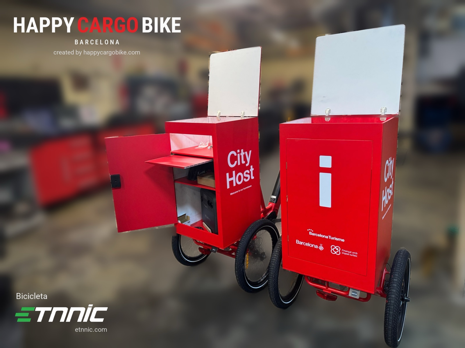 Dos triciclos rojos City Host de Barcelona Turisme en el taller de Happy Cargo Bike: cajón abierto con puerta lateral, bandeja abatible y estantes interiores, tapas blancas levantadas.